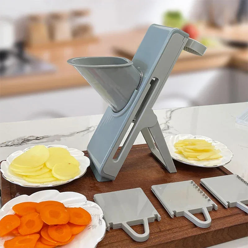 Adjustable kitchen mandoline slicer with blade attachments, slicing potatoes and carrots on a countertop.